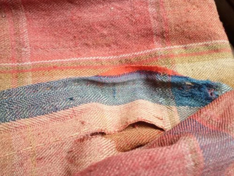 Close-up of the original Dalriada tartan showing preserved colours beneath the fold — the original crimson and blue protected for nearly 300 years